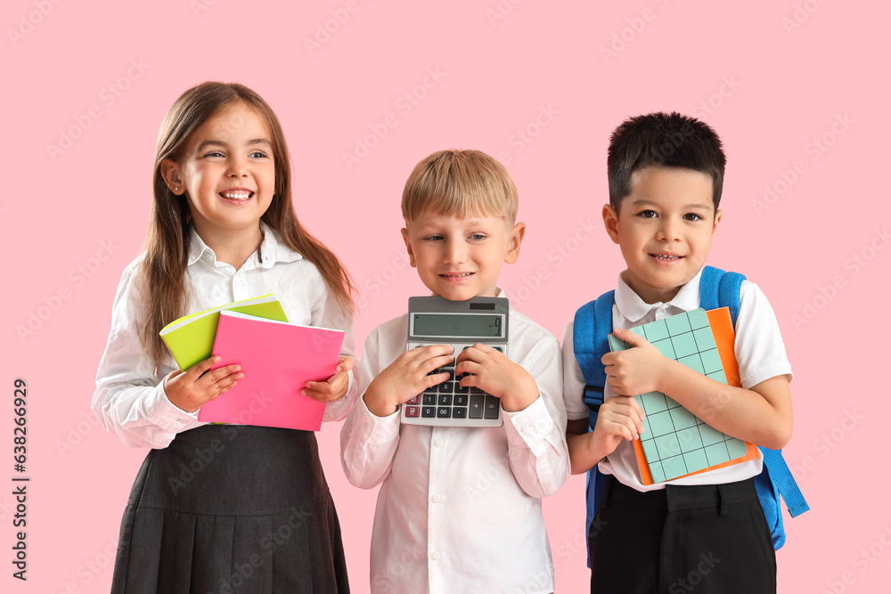 Little school children with stationery on pink background