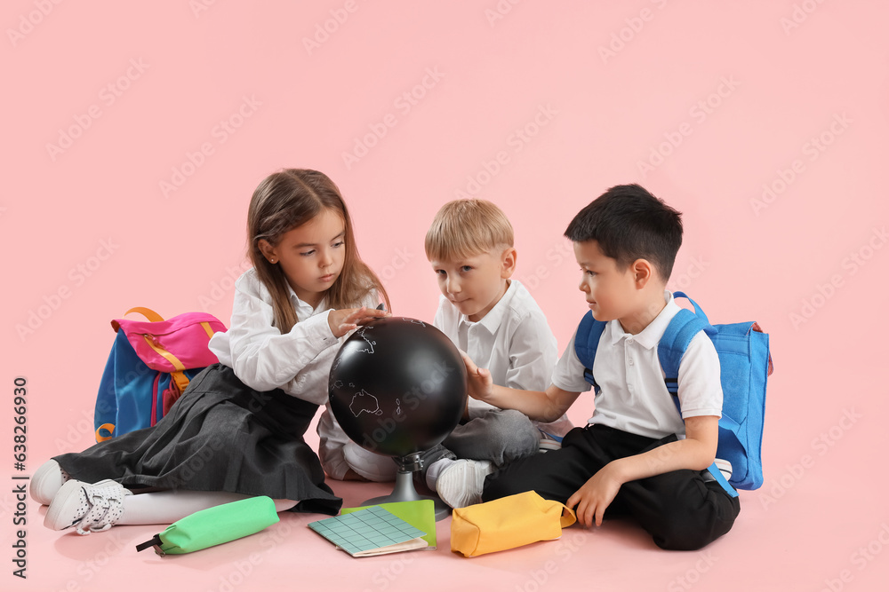 Little school children with globe on pink background