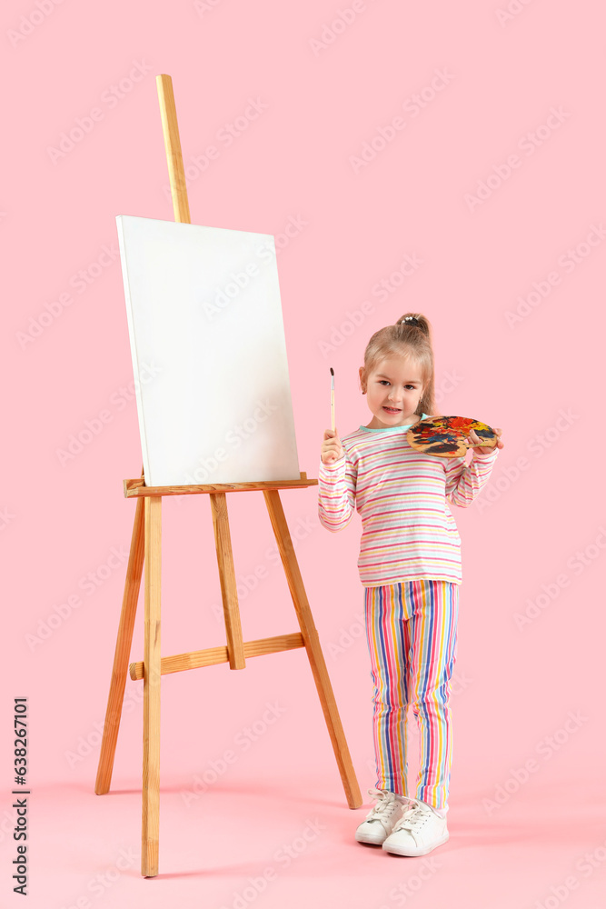 Cute little girl with paint palette, brush and easel on pink background