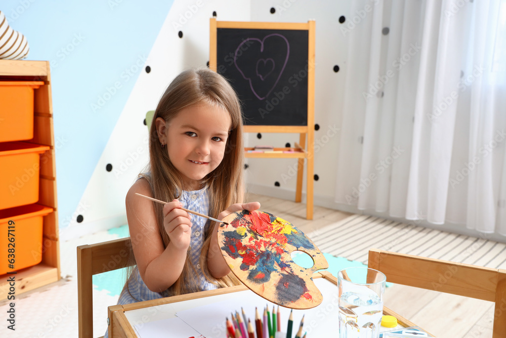 Cute little girl with paint palette at home