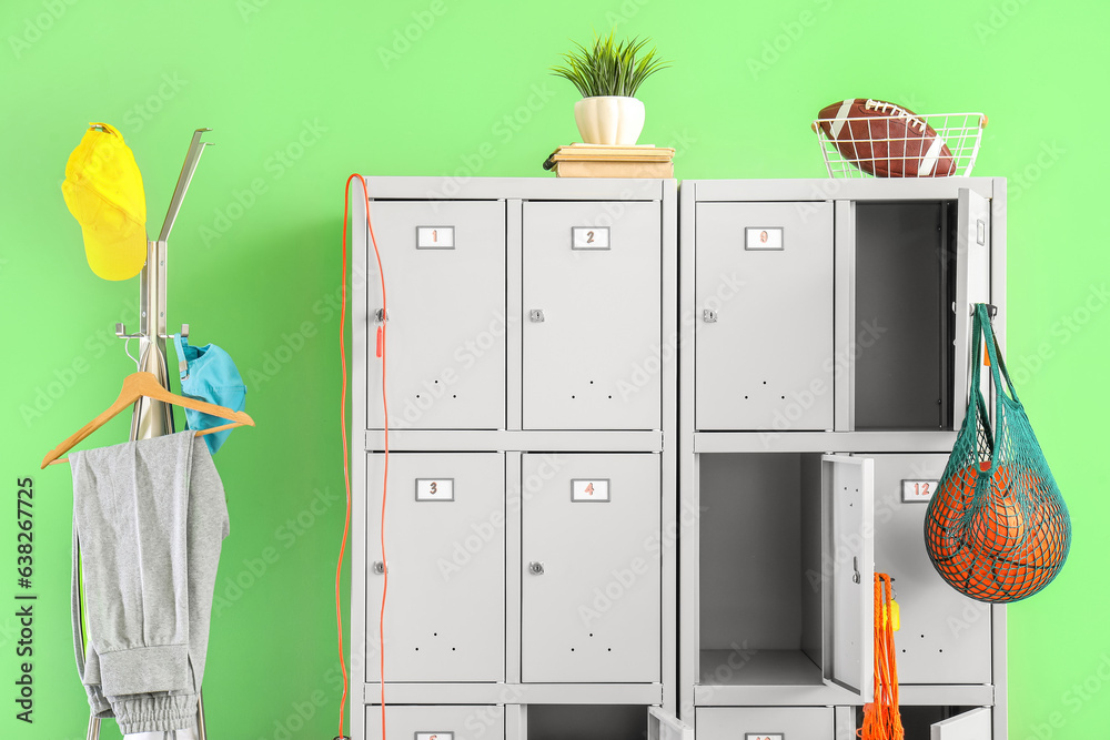 Modern locker with sports equipment and rack near green wall