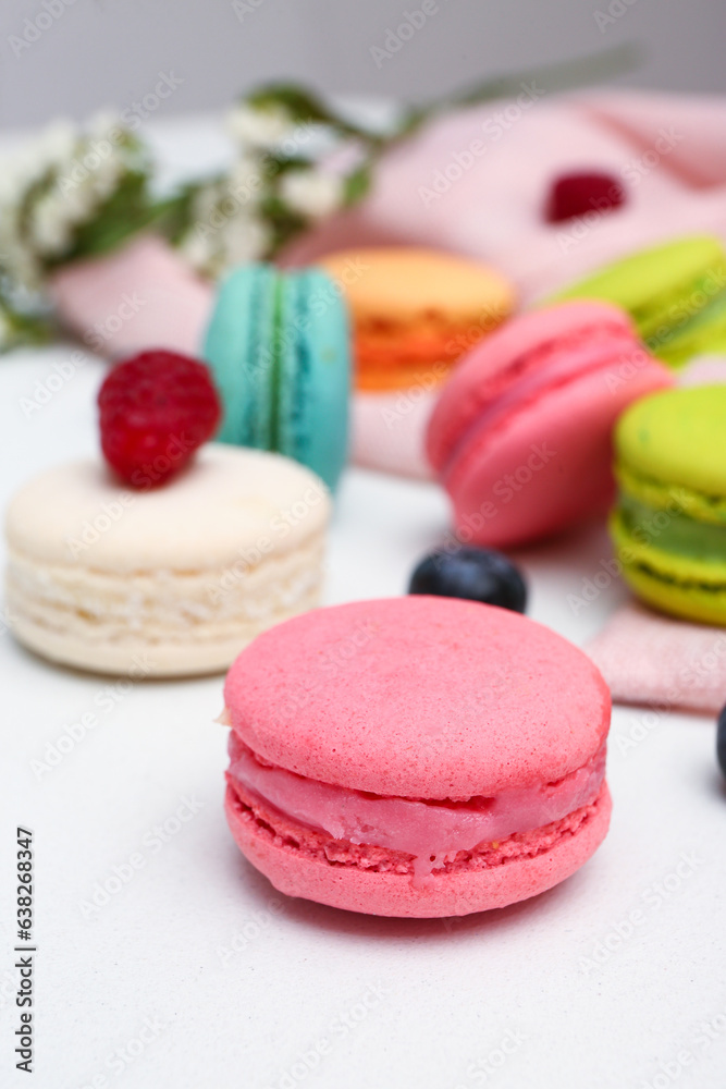 Sweet macaroons and berries on white background