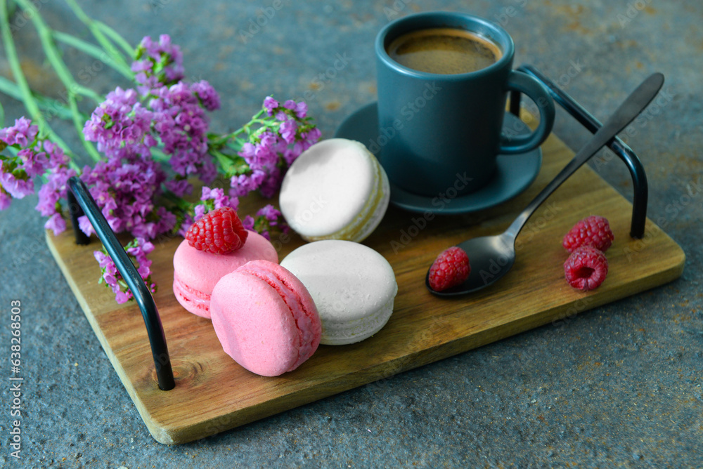 Wooden tray with sweet macaroons and cup of coffee on dark background