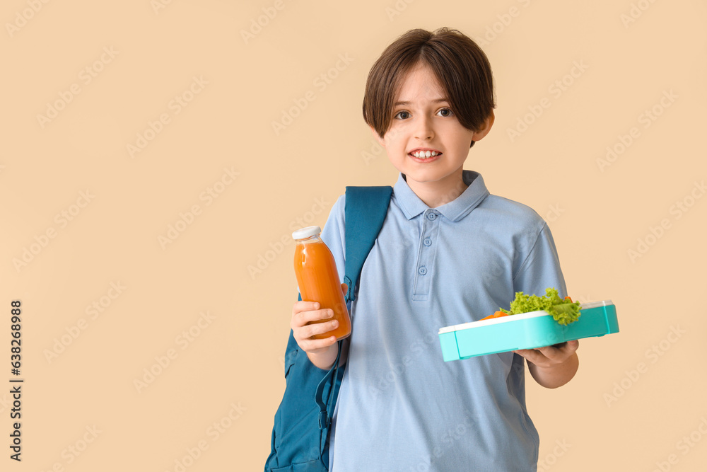 Little boy with backpack, bottle of juice and lunchbox on beige background