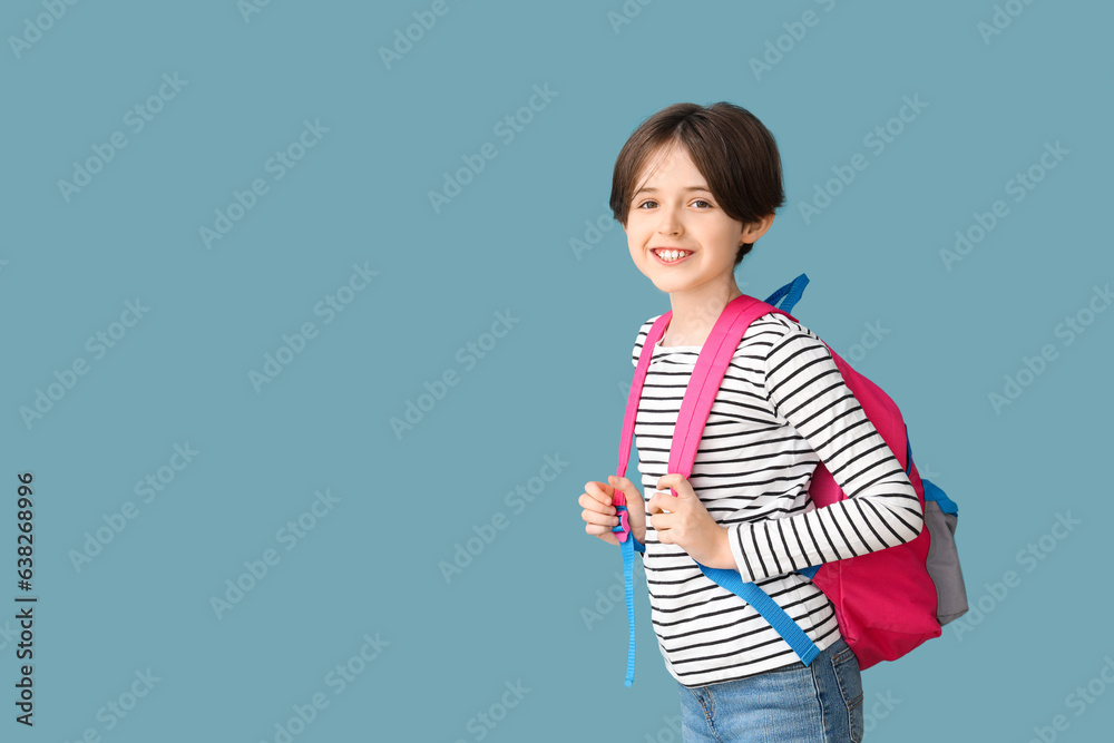 Happy little boy with backpack on blue background