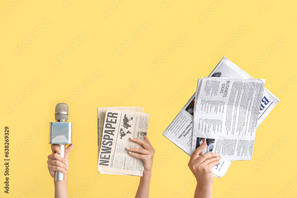 Female hands with microphone and newspapers on color background