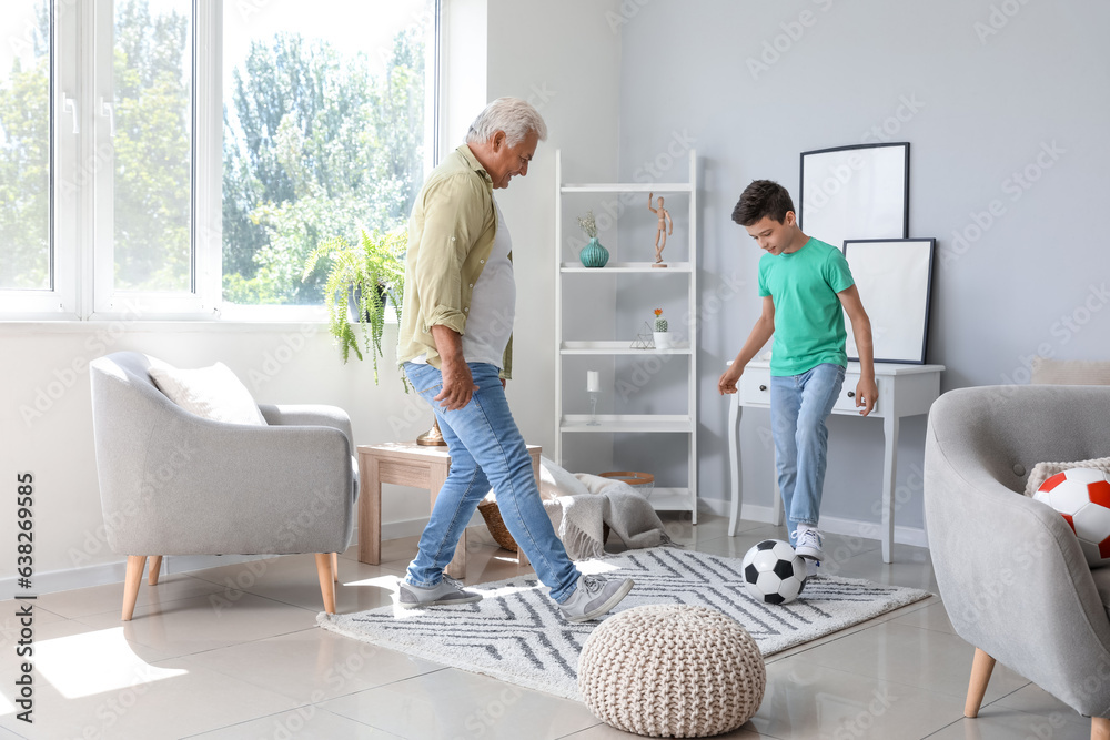 Little boy with his grandfather playing football at home