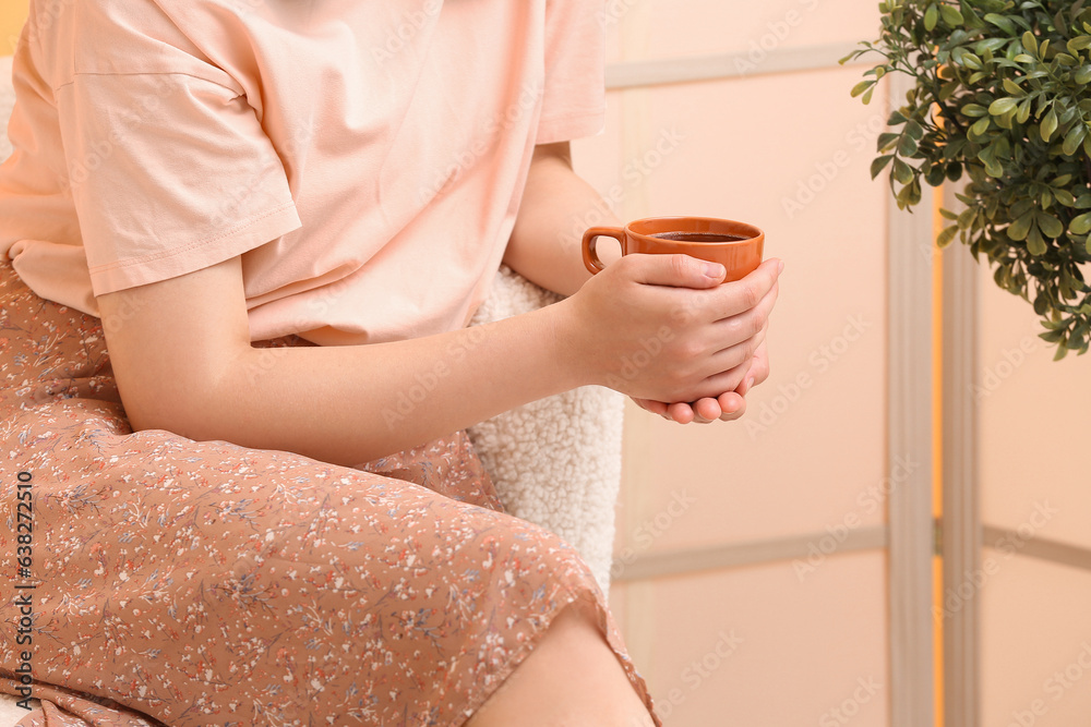 Woman holding cup of tasty coffee at home, closeup