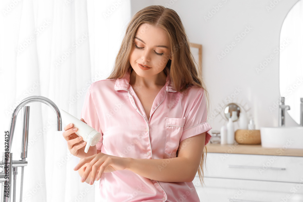 Young woman applying cream in bathroom