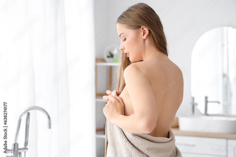 Young woman wiping with towel after shower in bathroom