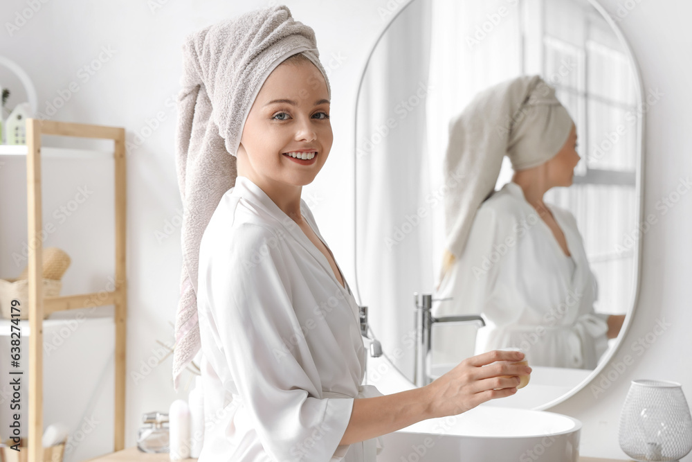 Young woman with cream after shower near mirror in bathroom