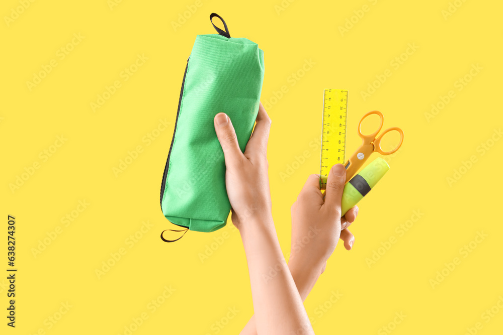 Female hands with different stationery on yellow background