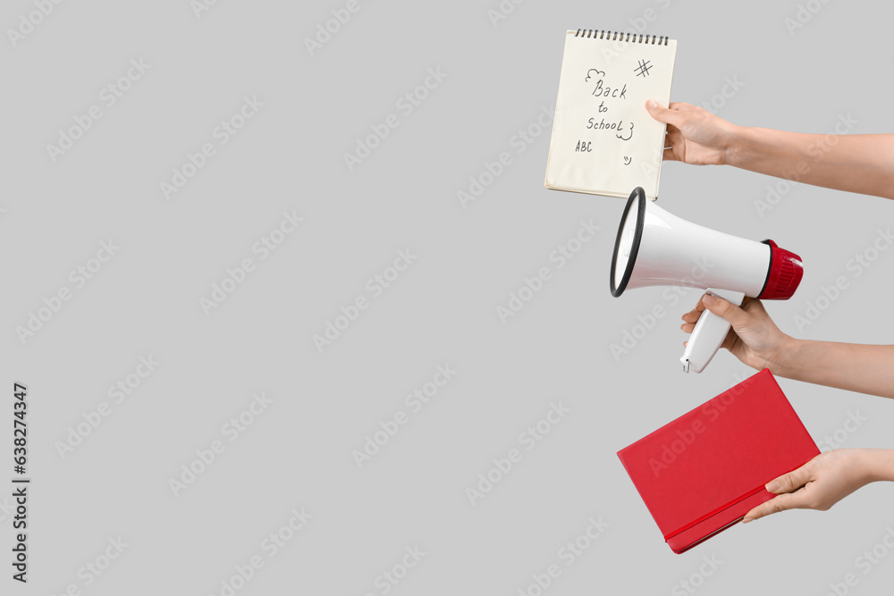 Female hands holding megaphone and notebooks with text BACK TO SCHOOL on grey background