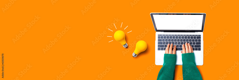 Person using a laptop computer and light bulbs - Flat lay