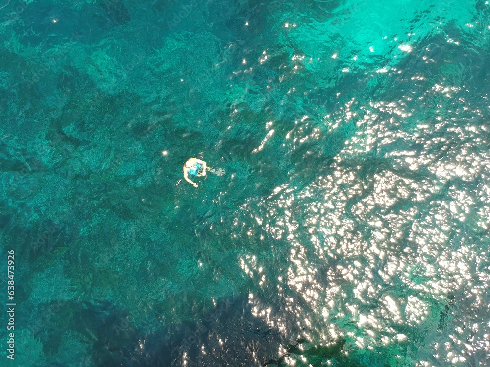 Above, swimming and a person in the ocean in summer for a beach vacation, travel or relax in the wat