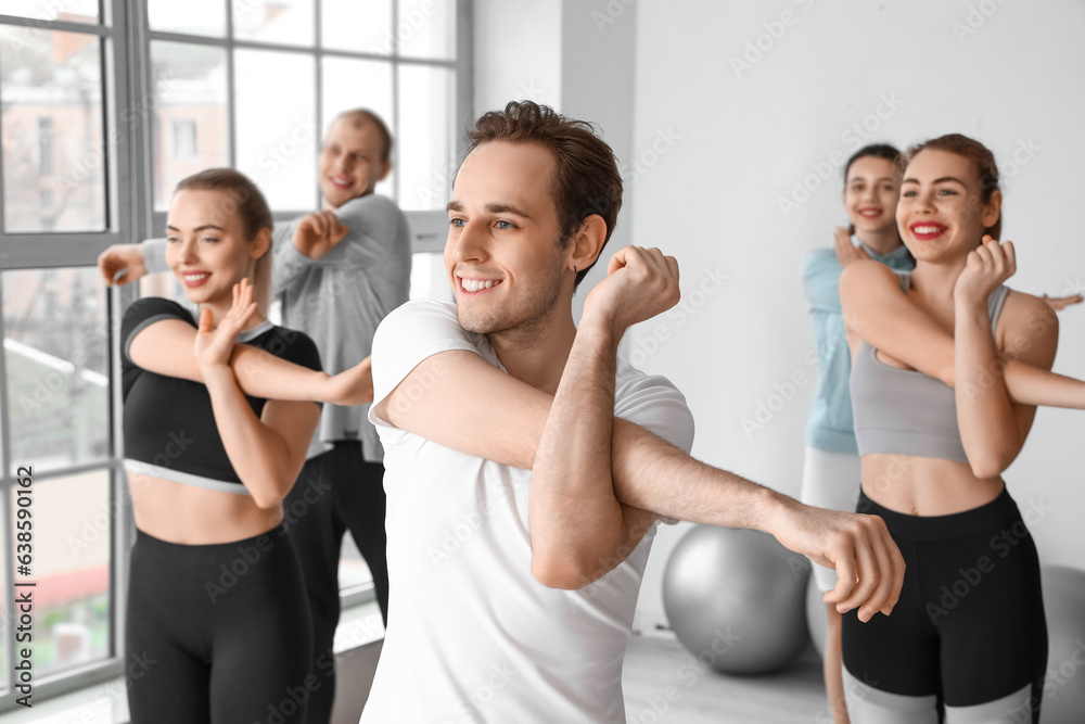 Sporty young man training with group in gym