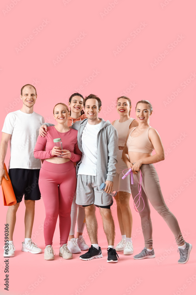 Group of sporty young people with equipment on pink background