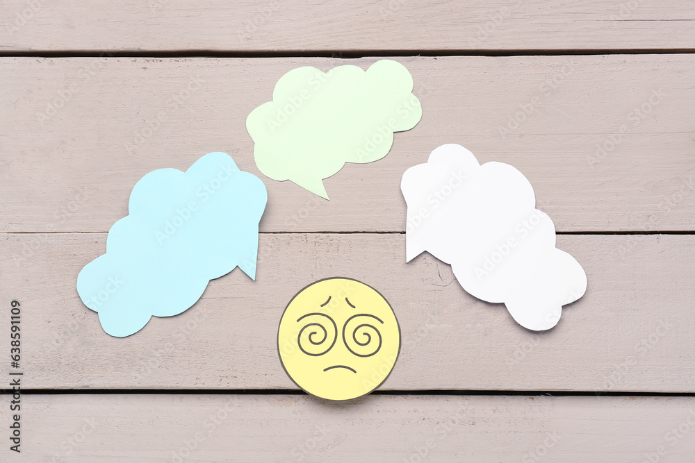 Confused paper face with blank speech bubbles on grey wooden background