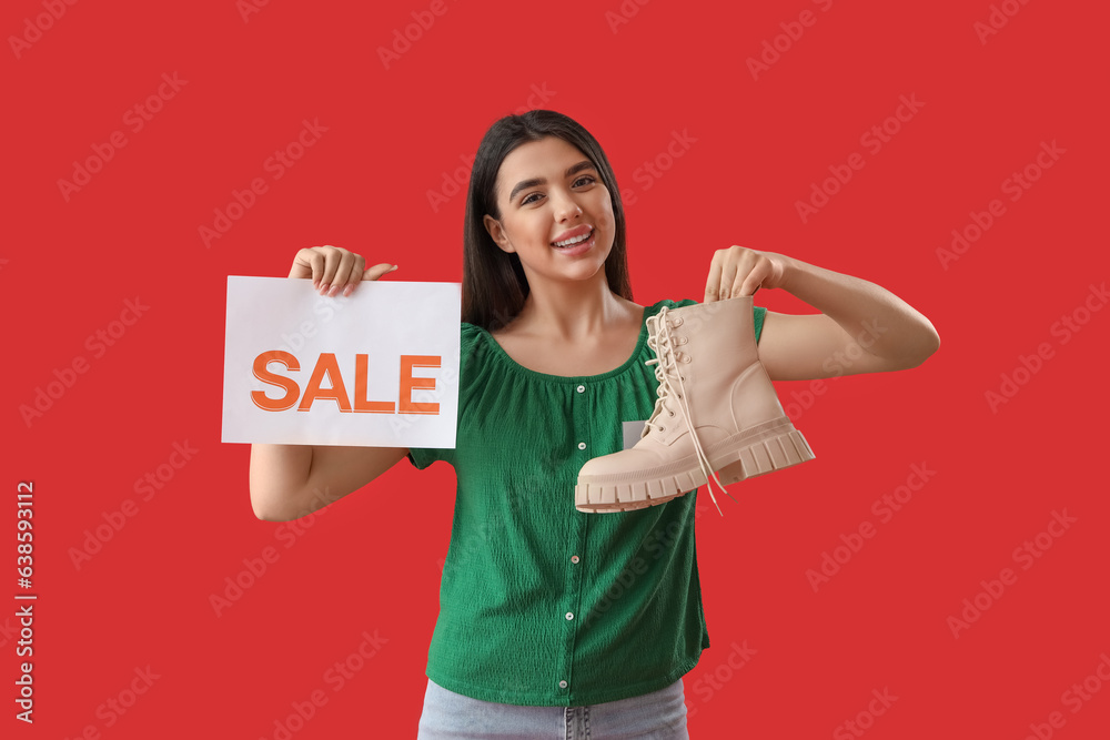 Female seller with sale sign and stylish boot on red background