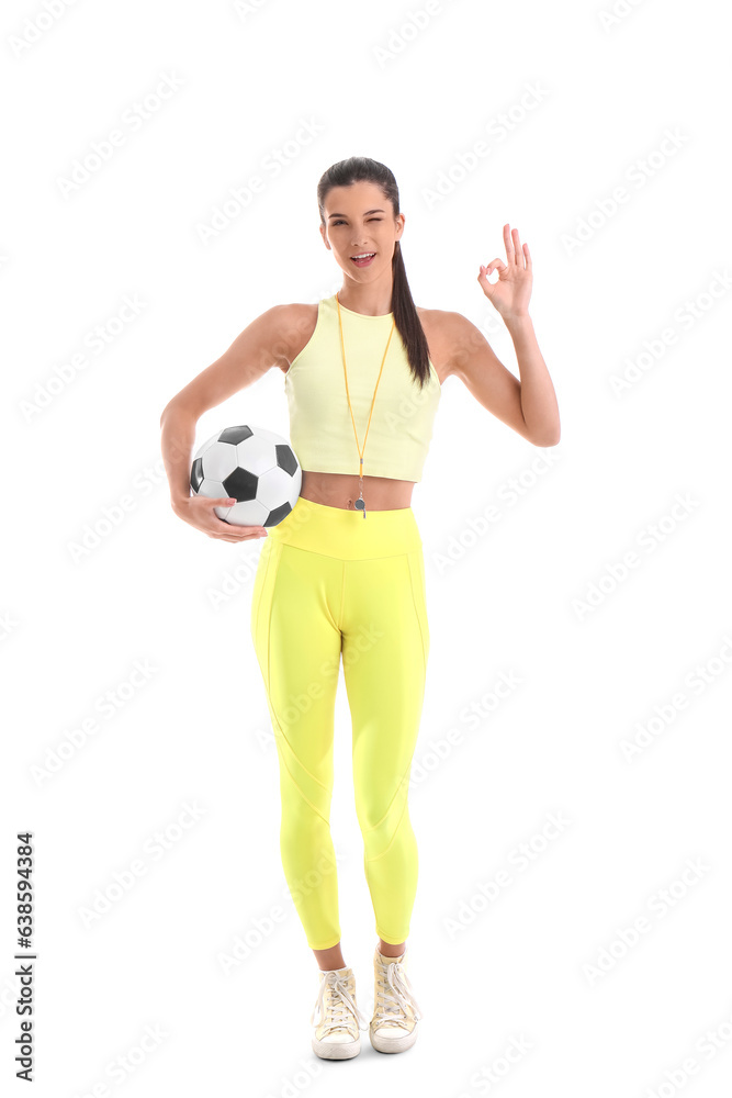 Sporty female coach with soccer ball showing OK on white background