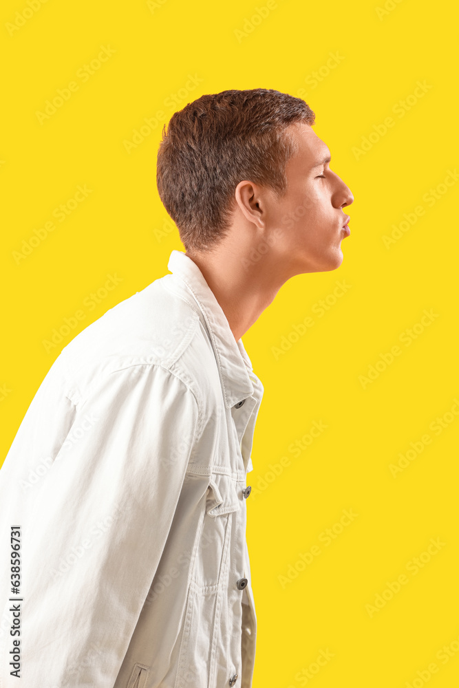 Young man blowing kiss on yellow background