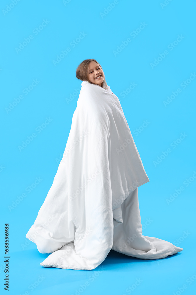 Little girl wrapped in blanket on blue background