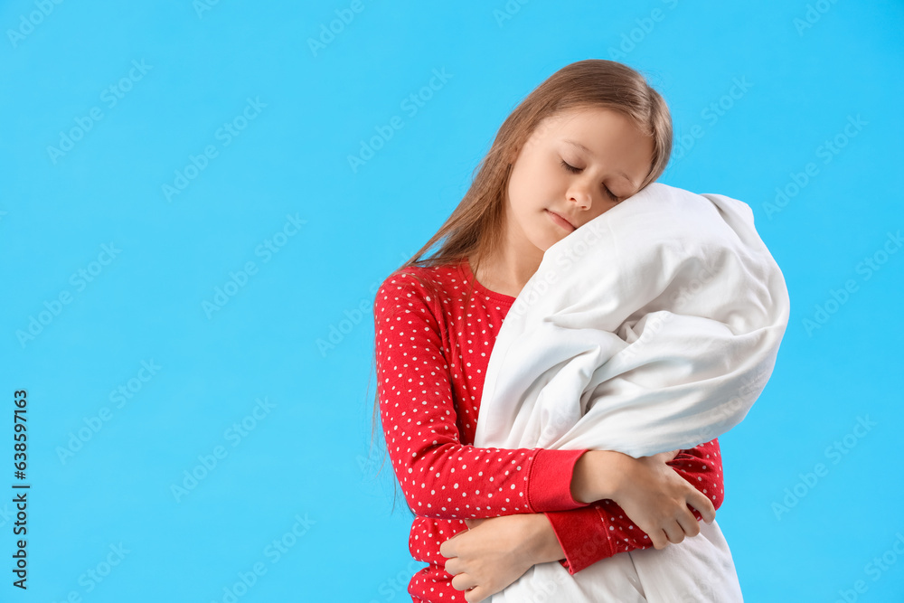 Sleepy little girl with blanket on blue background