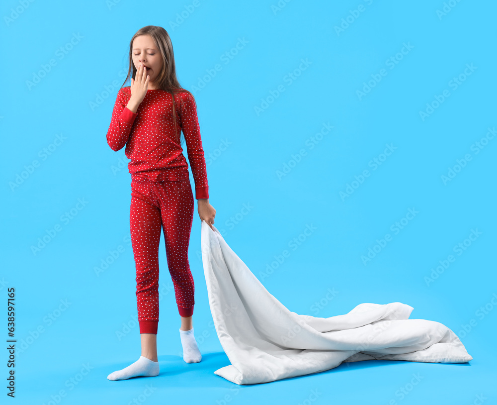 Sleepy little girl with blanket on blue background