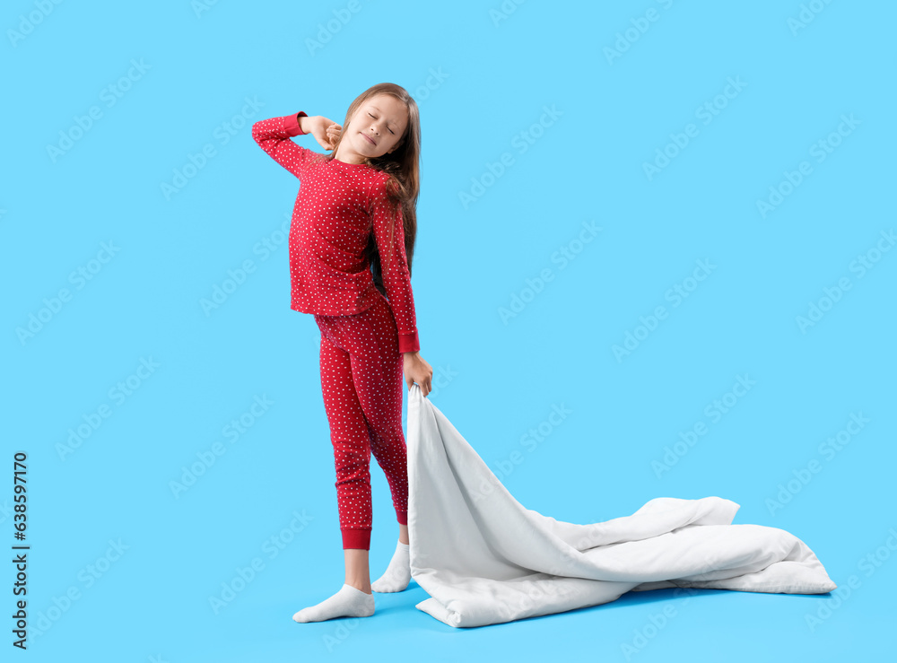 Sleepy little girl with blanket on blue background