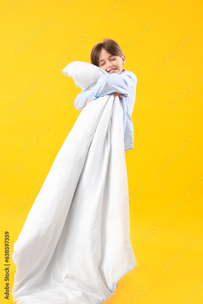 Cute little boy with blanket on yellow background