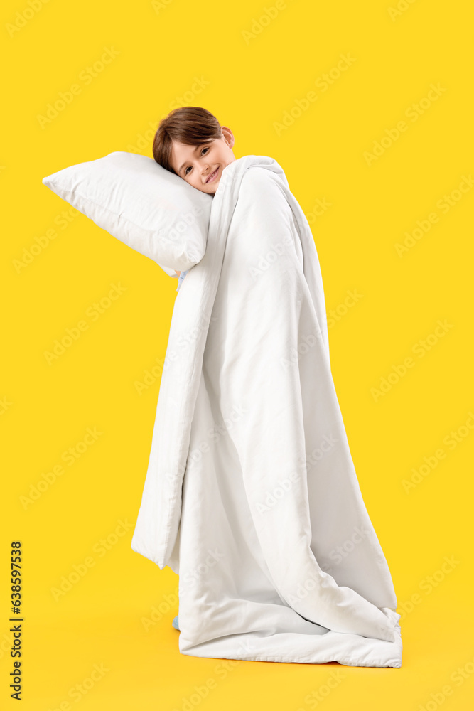 Sleepy little boy with pillow and blanket on yellow background