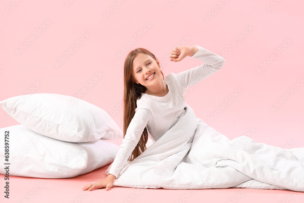 Little girl with pillow and blanket on pink background