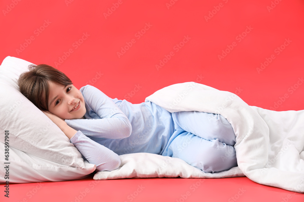 Little boy with pillow and blanket on red background