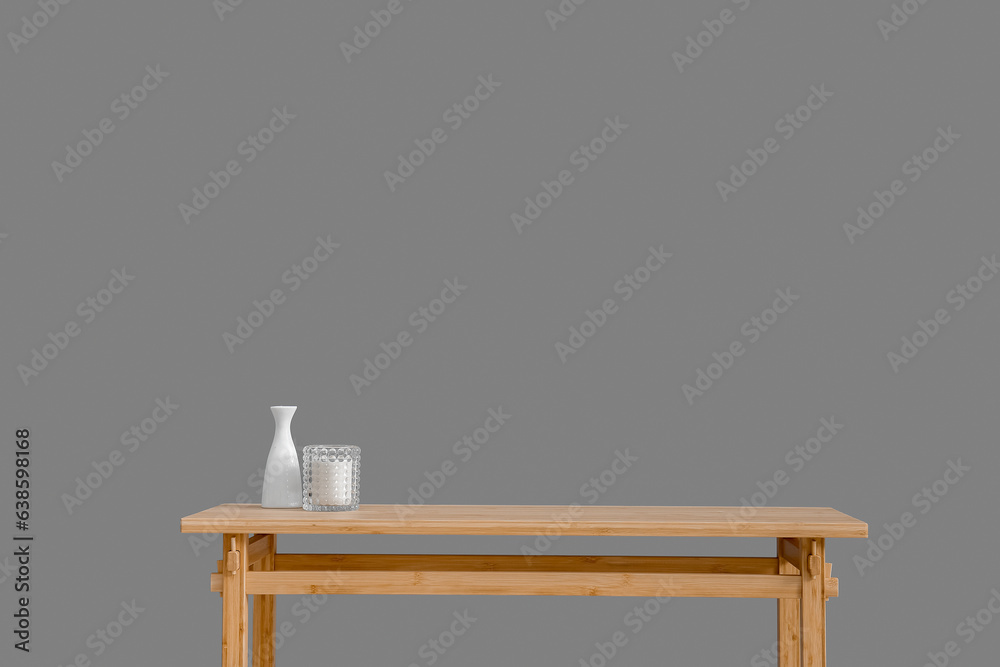 Wooden table with empty vase and candle near grey wall