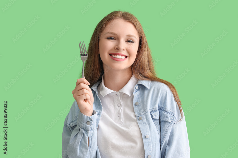 Young woman with fork on green background