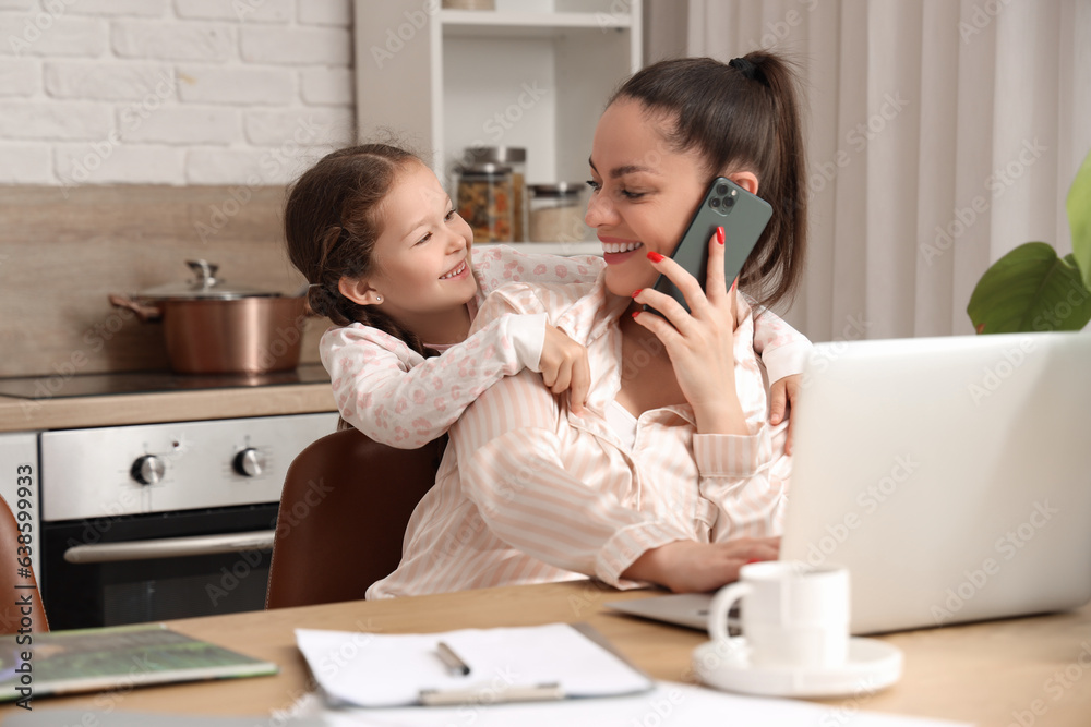 Working mother with her little daughter in kitchen