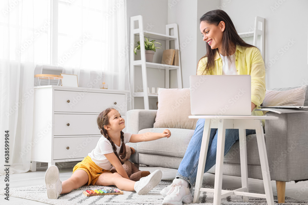 Little girl playing with xylophone while her mother working at home