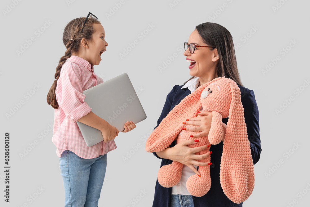 Little girl with her working mother on light background