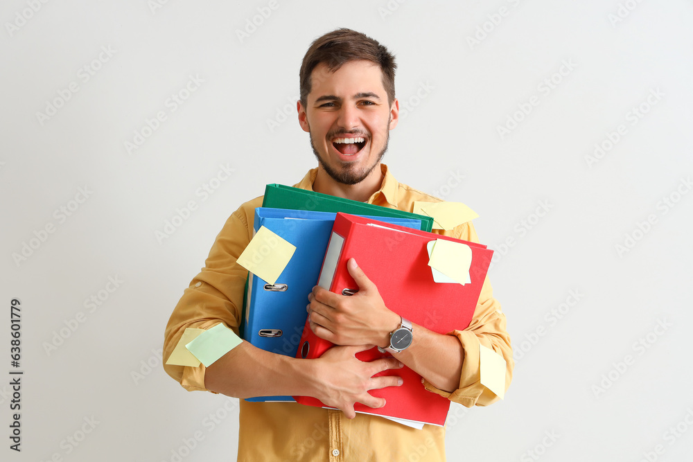 Stressed young man with folders on light background. Deadline concept