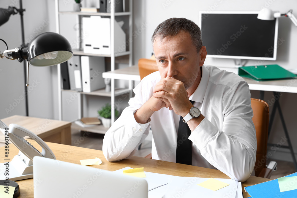 Stressed mature businessman working under deadline in office