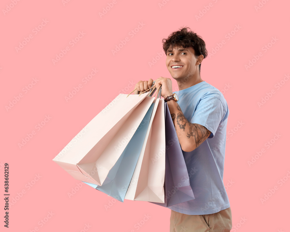 Young man with shopping bags on pink background