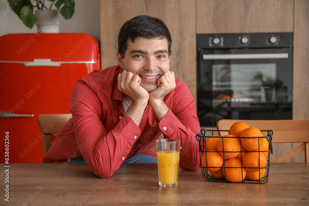 Young man with glass of orange juice in kitchen