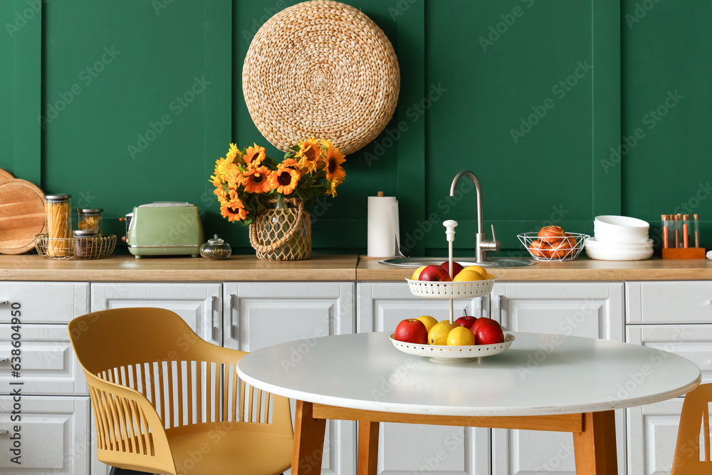 Interior of modern kitchen with white counters and dining table