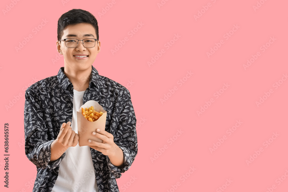 Young Asian man with french fries making heart gesture on pink background