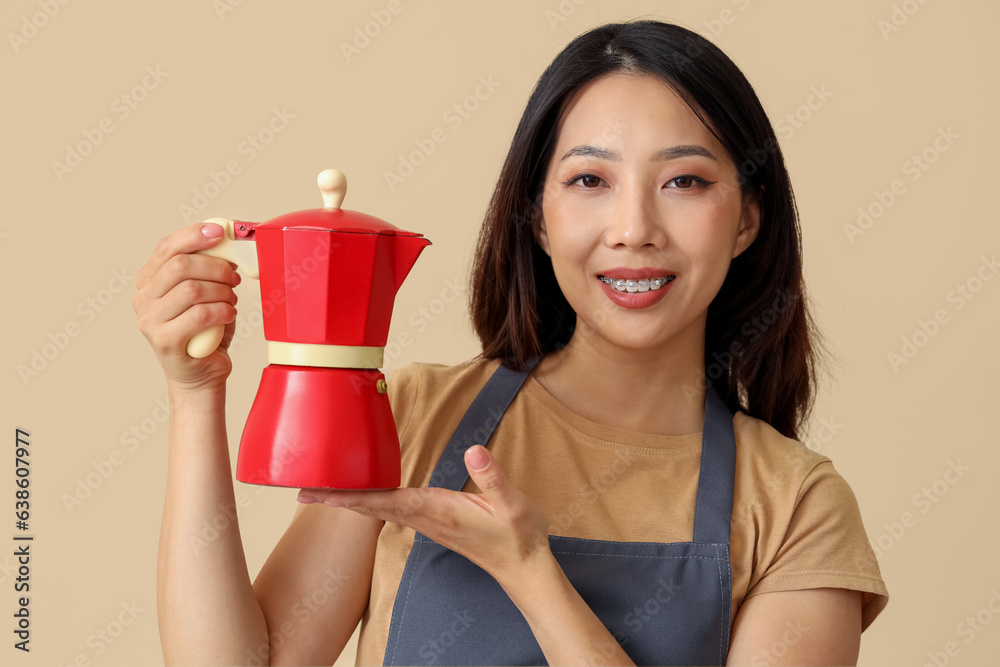 Happy beautiful Asian woman with geyser coffee maker on beige background