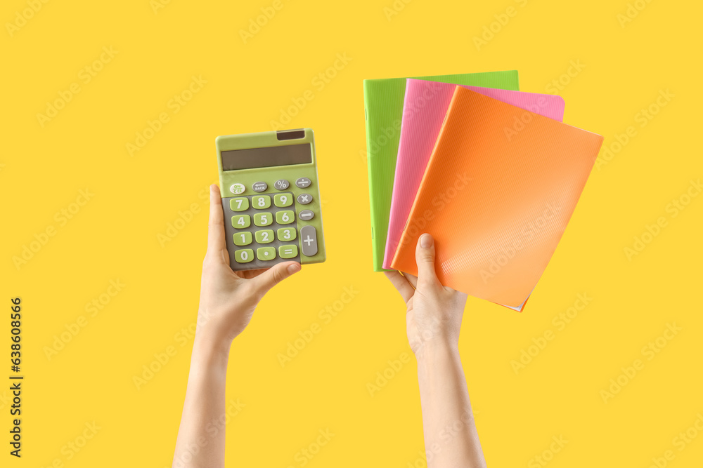 Hands with notebooks and calculator on yellow background