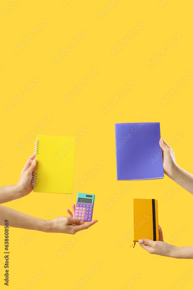 Hands with calculator and set of stationery on yellow background