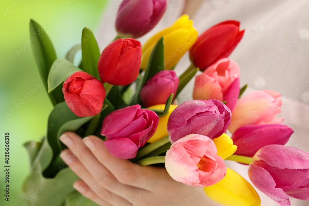 Woman holding beautiful colorful tulip flowers on blurred background, closeup