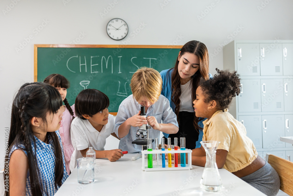 Adorable student learn with teacher in classroom at elementary school. 