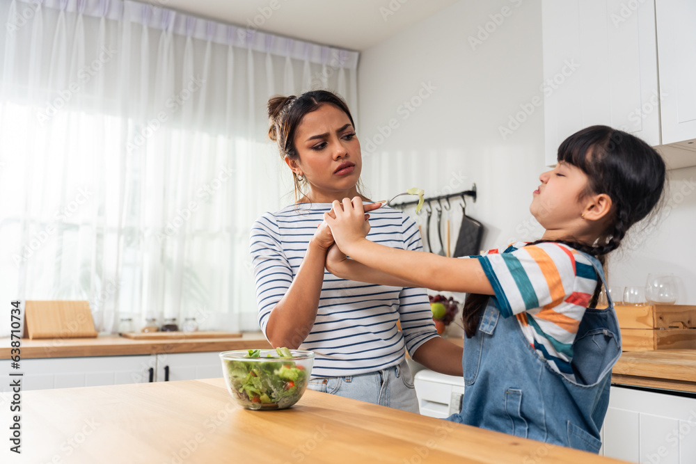 Caucasian mother teach and motivate young daughter eat green vegetable. 